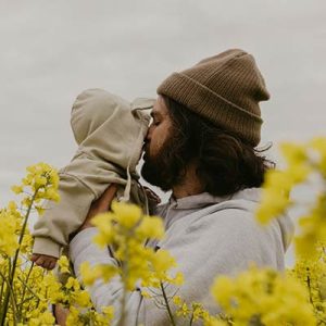 bearded-man-hugging-young-baby-in-flower-field