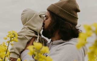 bearded-man-hugging-young-baby-in-flower-field