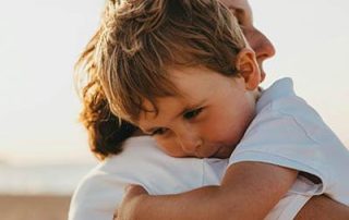 young-boy-hugging-mum-on-beach